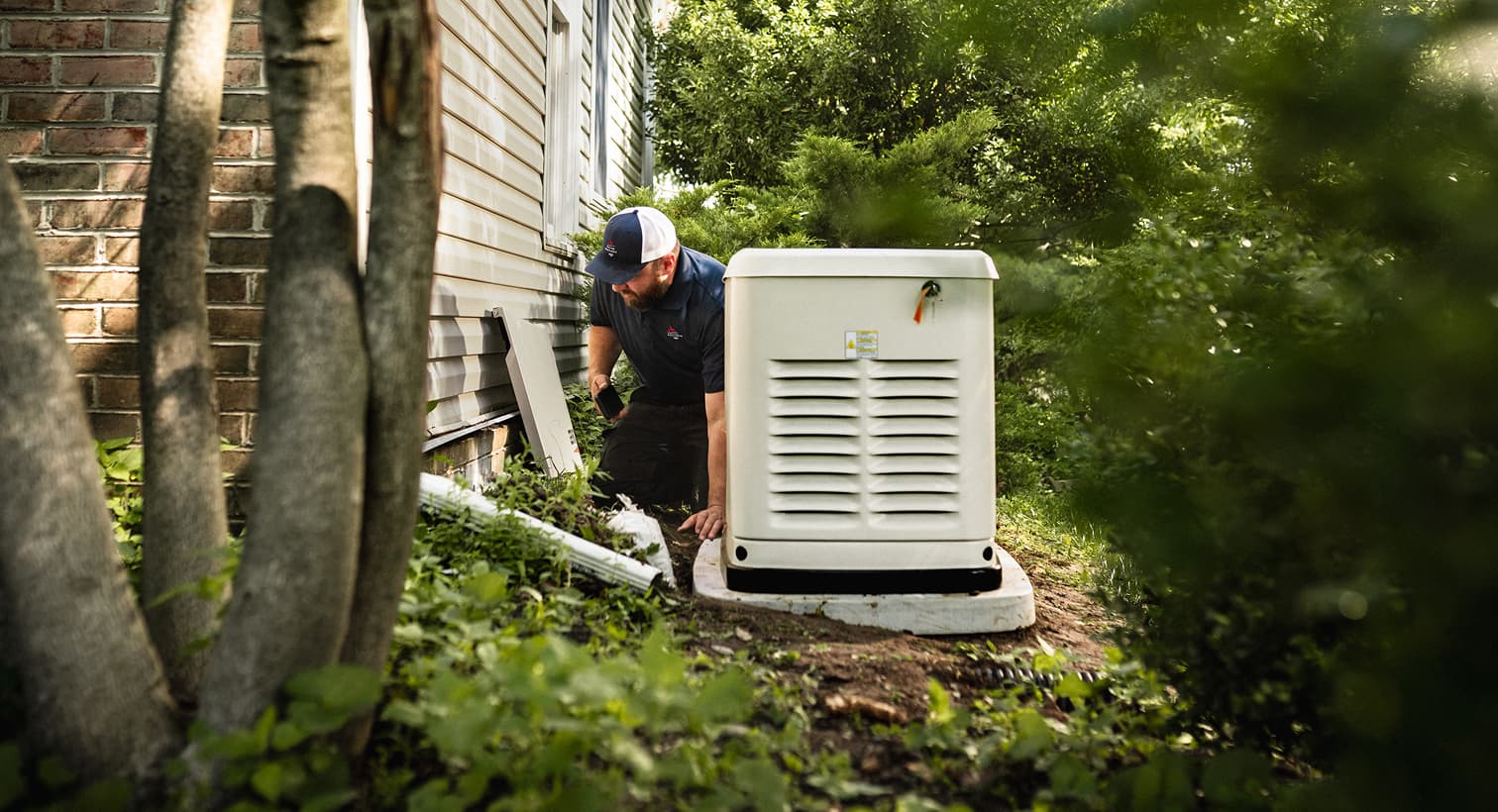A professional Gevais technician inspects a large, beige whole-home standby generator installed on a concrete pad outside a residential house.