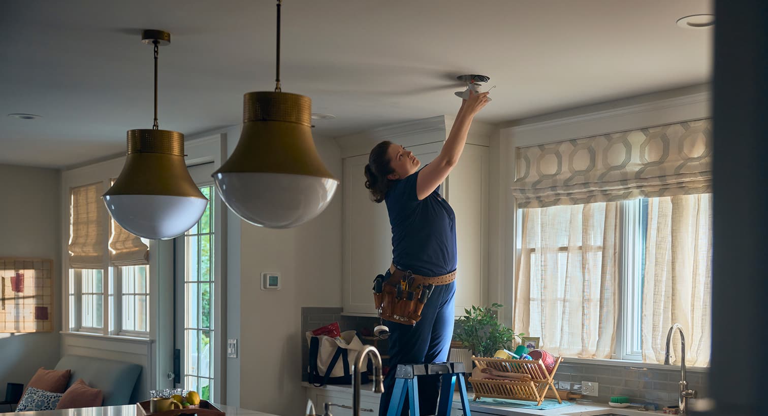 A professional Gervais electrician standing on a ladder to install modern recessed ceiling lights during a residential electrical installation service.