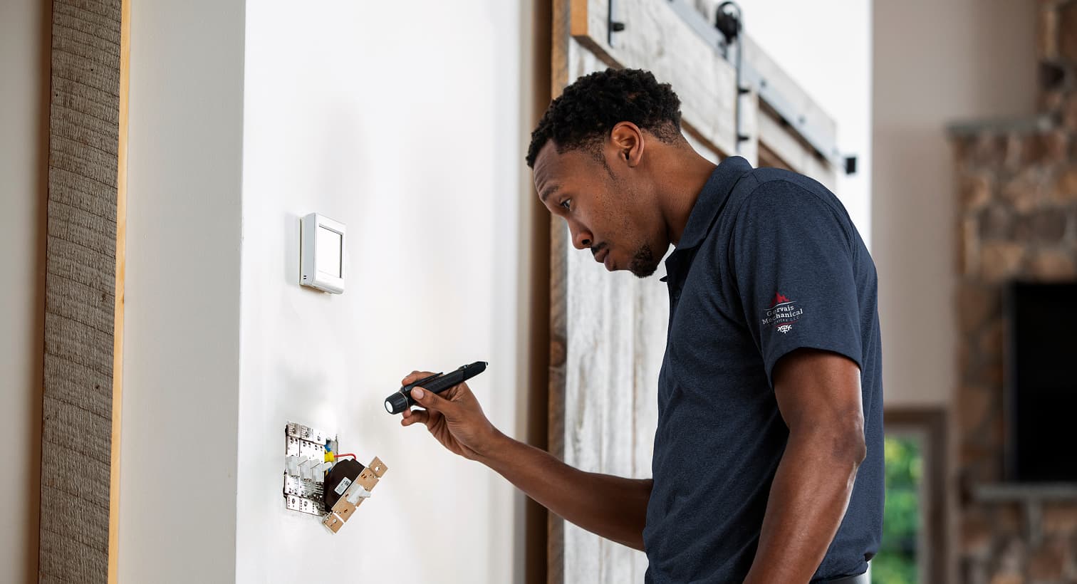 A professional Gervais electrician using a flashlight to safely inspect and troubleshoot exposed residential wall switch wiring during an electrical repair service.